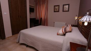 A bedroom with a bed, a chair, a radiator, and a lamp.