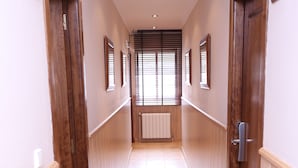 Un pasillo con puertas de madera, un radiador y una ventana con persianas.