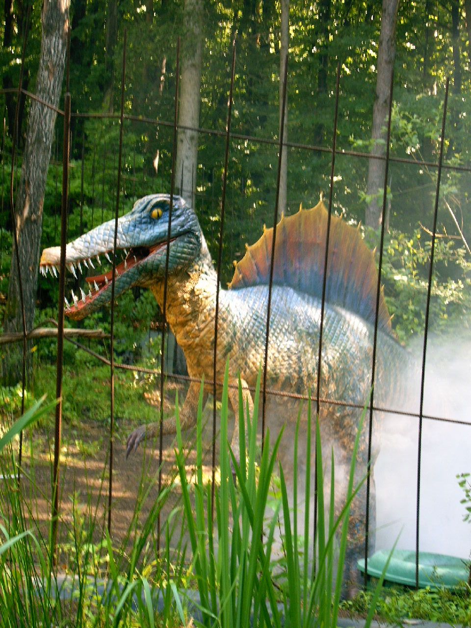 Una exhibición de dinosaurios con un modelo grande y detallado de un dinosaurio detrás de una cerca.
