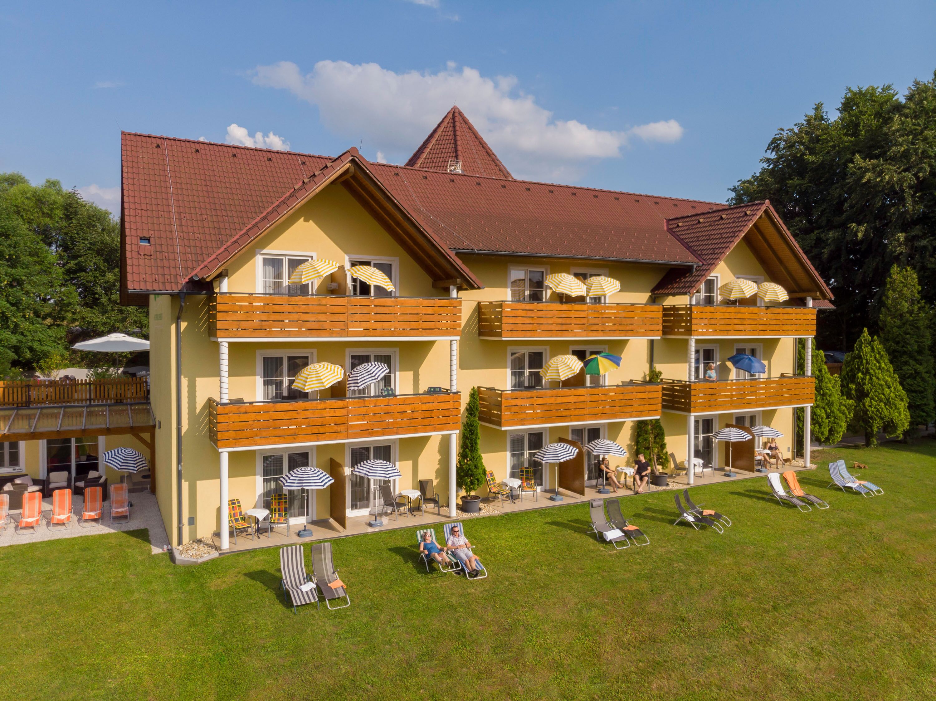 A multi-story hotel with balconies, outdoor seating, and umbrellas.