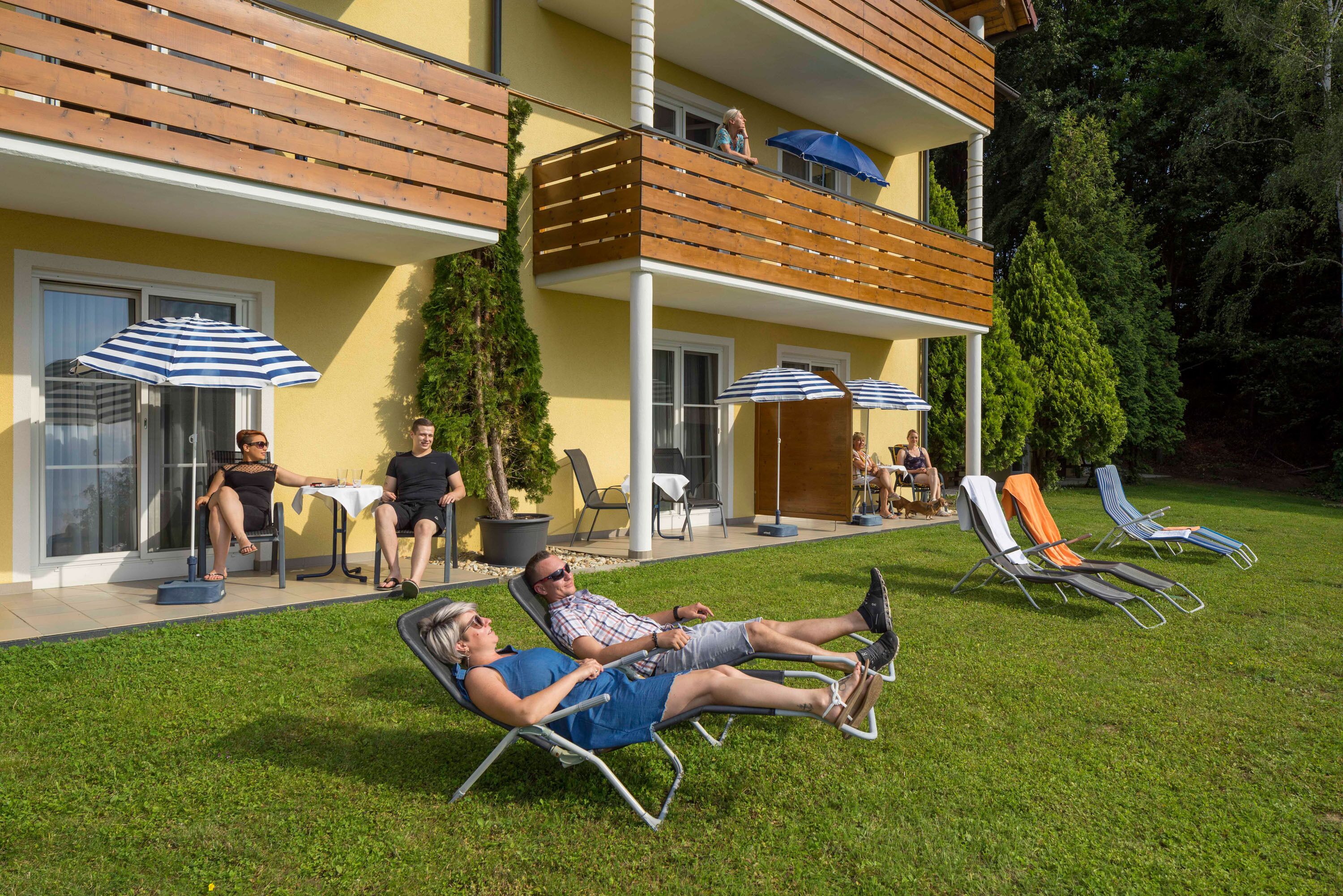 Un bâtiment à deux étages doté d’un balcon, d’un espace extérieur aménagé pour s’asseoir et d’une pelouse.