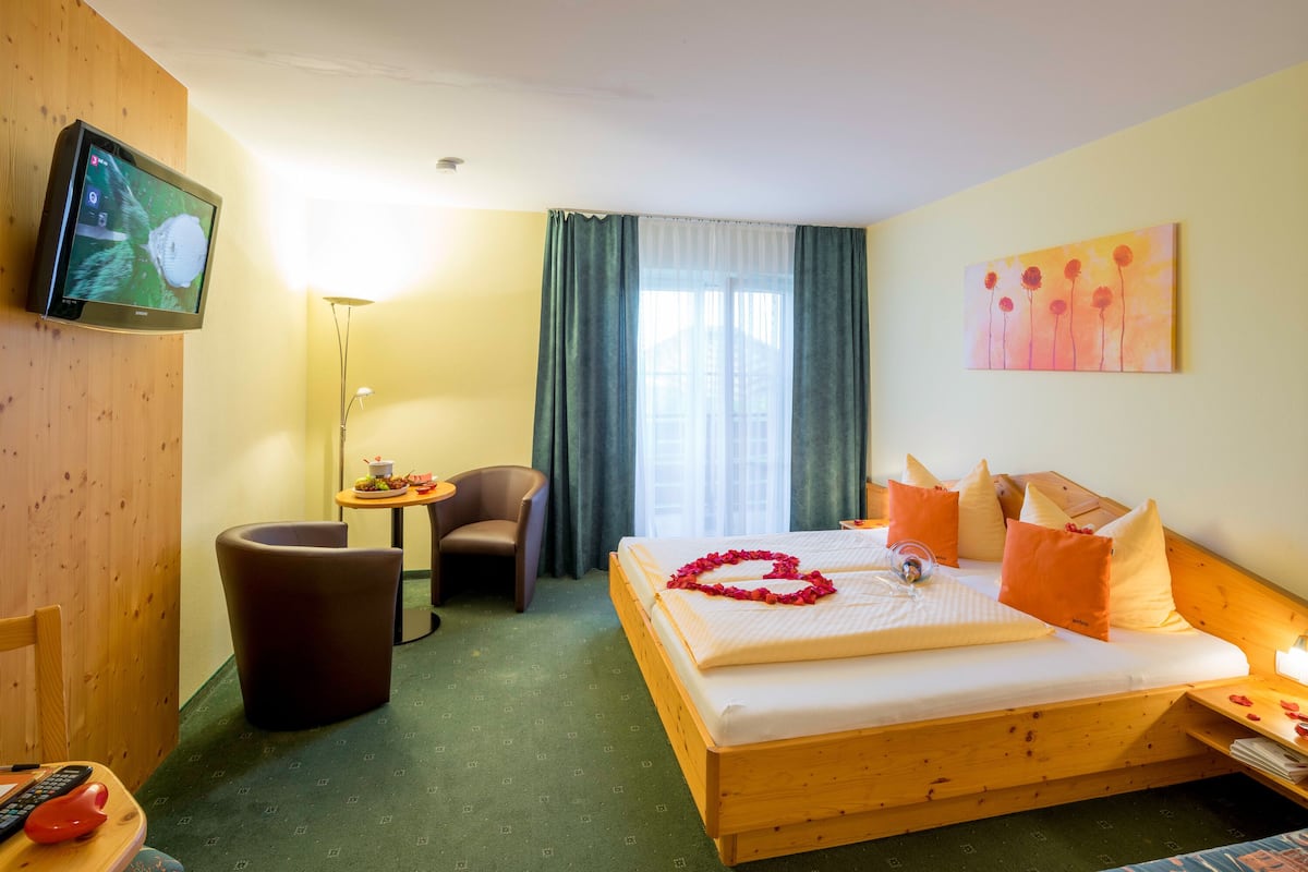 Une chambre d’hôtel avec un lit, une télévision, une chaise, une petite table avec une lampe et un tableau au mur.