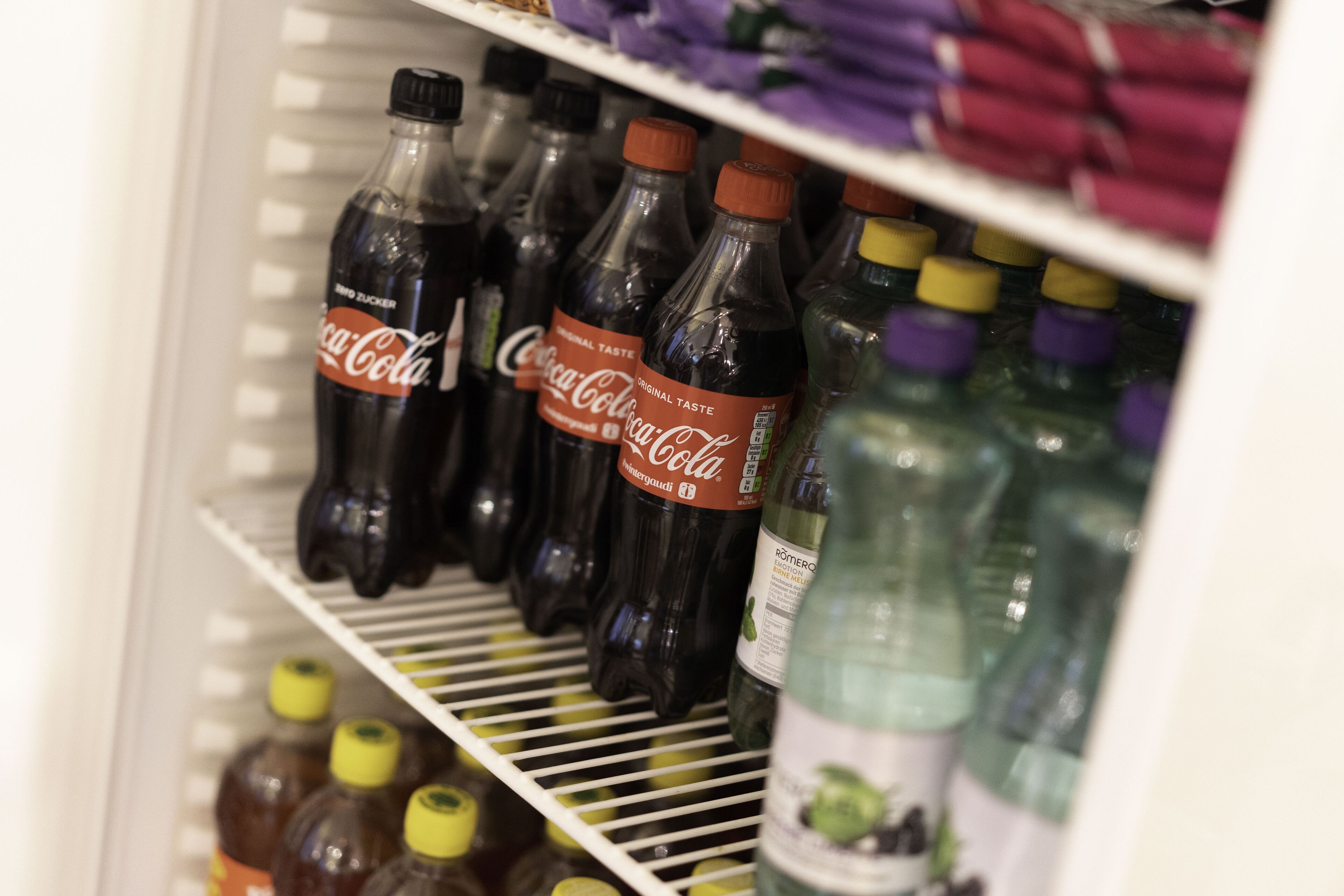 Ein gekühlter Warenkorb mit verschiedenen Flaschen, darunter Coca-Cola und andere Getränke.