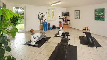 A gym with exercise equipment, a television, and a poster on the wall.