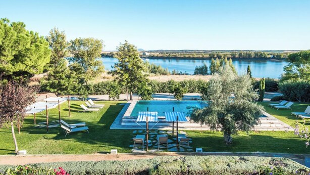 Zona de piscina con sillones de descanso y vistas a un lago.