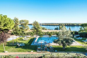 Zona de piscina con sillones de descanso y vistas a un lago.