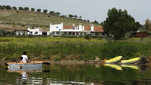 Un río tranquilo con una casa y un bote en primer plano.