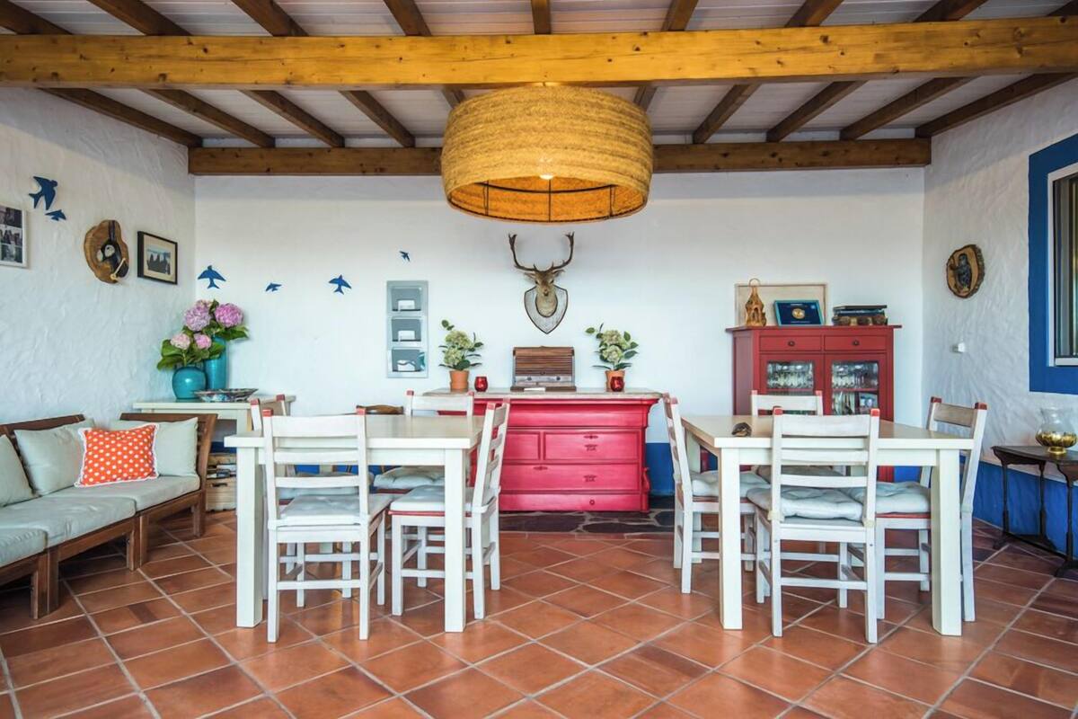 Un coin repas avec un plafond en bois, un buffet rouge et une tête de cerf accrochée au mur.