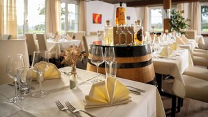 A dining table set with wine glasses, a bottle of liquor, and a decorative vase. - Hotel & Gasthaus die Perle (Perlen)