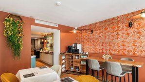 A restaurant with a bar area, tables with white tablecloths, and a patterned wall. - Hotel Molière (Cannes)
