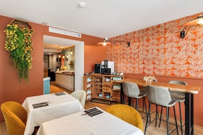 A restaurant with a bar area, tables with white tablecloths, and a patterned wall. - Hotel Molière (Cannes)