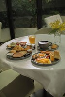 Een ontbijttafel met eieren, spek, toast en een glas sinaasappelsap.
