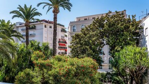 A residential area with multi-story buildings, palm trees, and lush greenery. - Hotel Molière (Cannes)