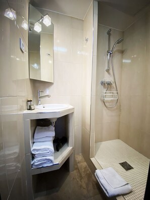 Baño con lavamanos, espejo, toallero y ducha.