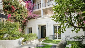 A multi-story building with balconies, a courtyard with artificial grass, outdoor seating, and potted plants. - Hotel Molière (Cannes)