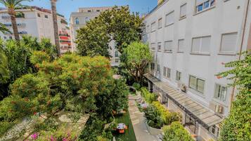 Une cour d’hôtel dotée d’un espace de repos central, entourée d’une végétation luxuriante et d’arbres.