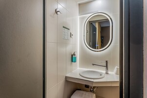 Een moderne badkamer met een witte wastafel, een spiegel en een handdoekhouder.