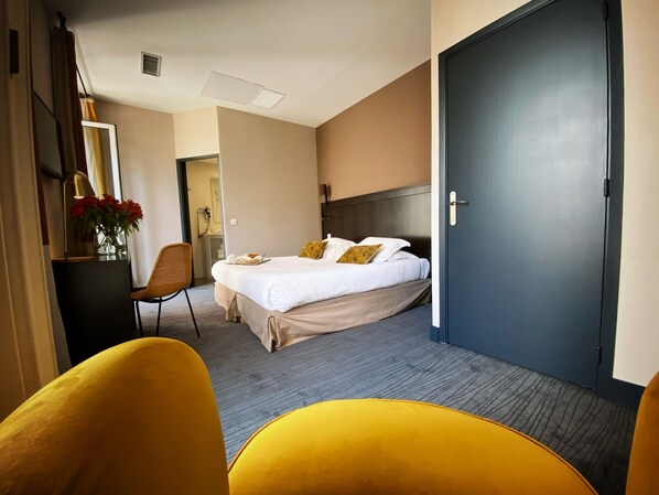 Una habitación de hotel con una cama, un escritorio con lámpara, una silla y una puerta.