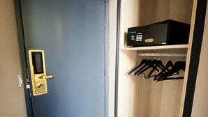 A room with a dark blue door, a small shelf with a microwave, and a rack of black hangers. - Hotel Molière (Cannes)