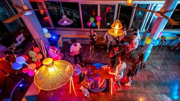 Um espaço interno amplo, com pé direito alto, grandes janelas e luminárias pendentes.