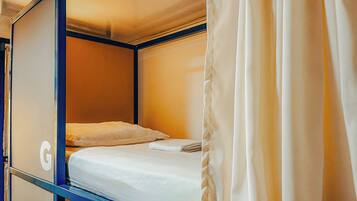 A single bed in a small, enclosed room with a wooden headboard and a curtain.