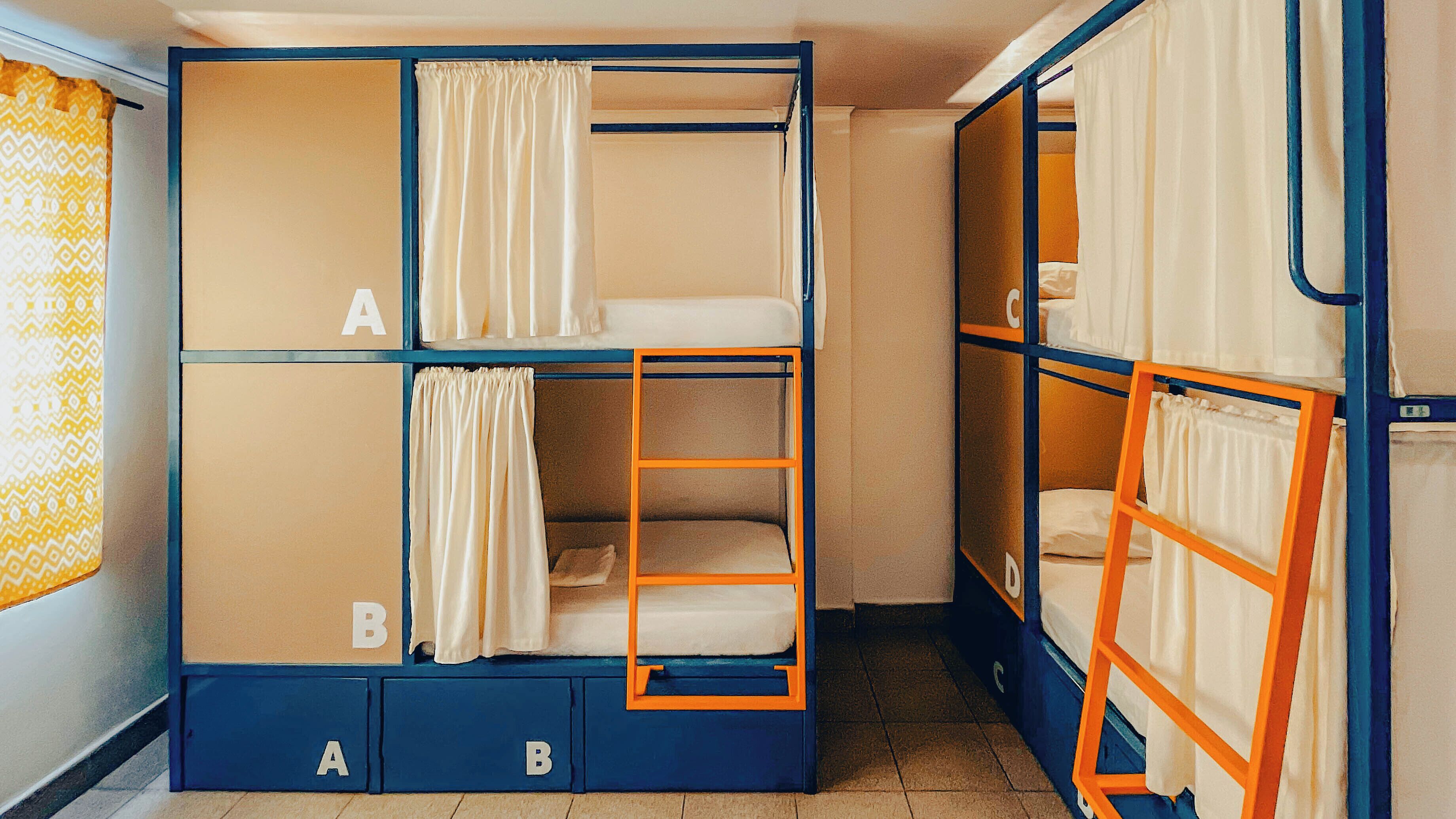 A dormitory room with bunk beds labeled A and B, each with a small drawer below.