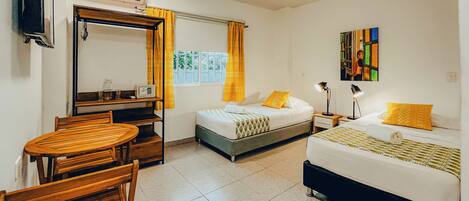 A hotel room with two beds, a desk, a chair, a TV, and a window with curtains.