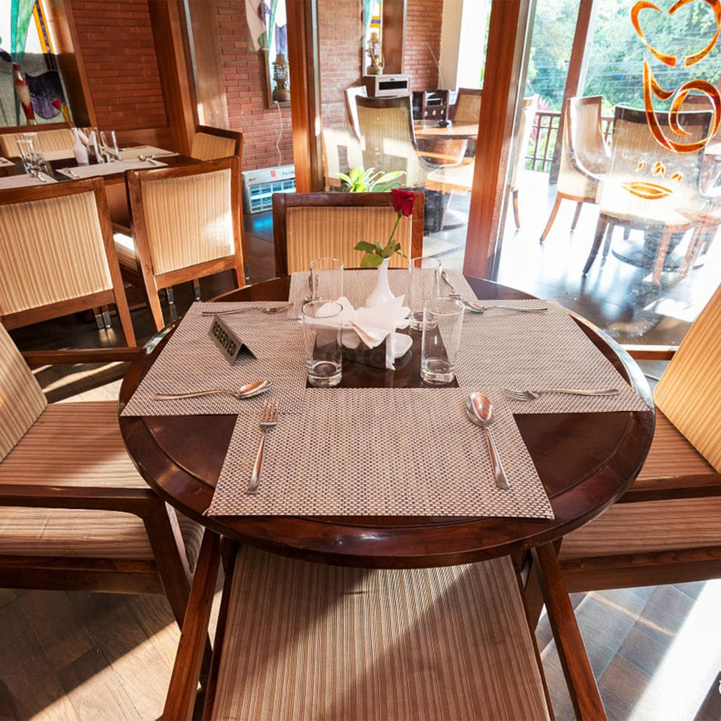 Une table de salle à manger ronde, avec un set de table, un vase contenant une seule rose et un panneau indiquant « RÉSERVÉ ».