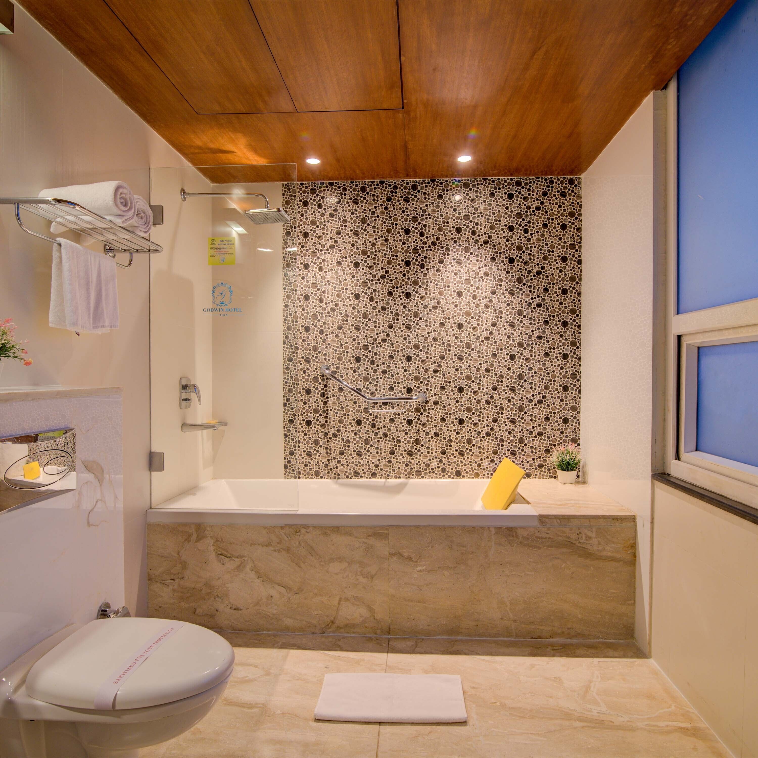 A bathroom with a wooden ceiling, a bathtub, a shower, and a toilet.