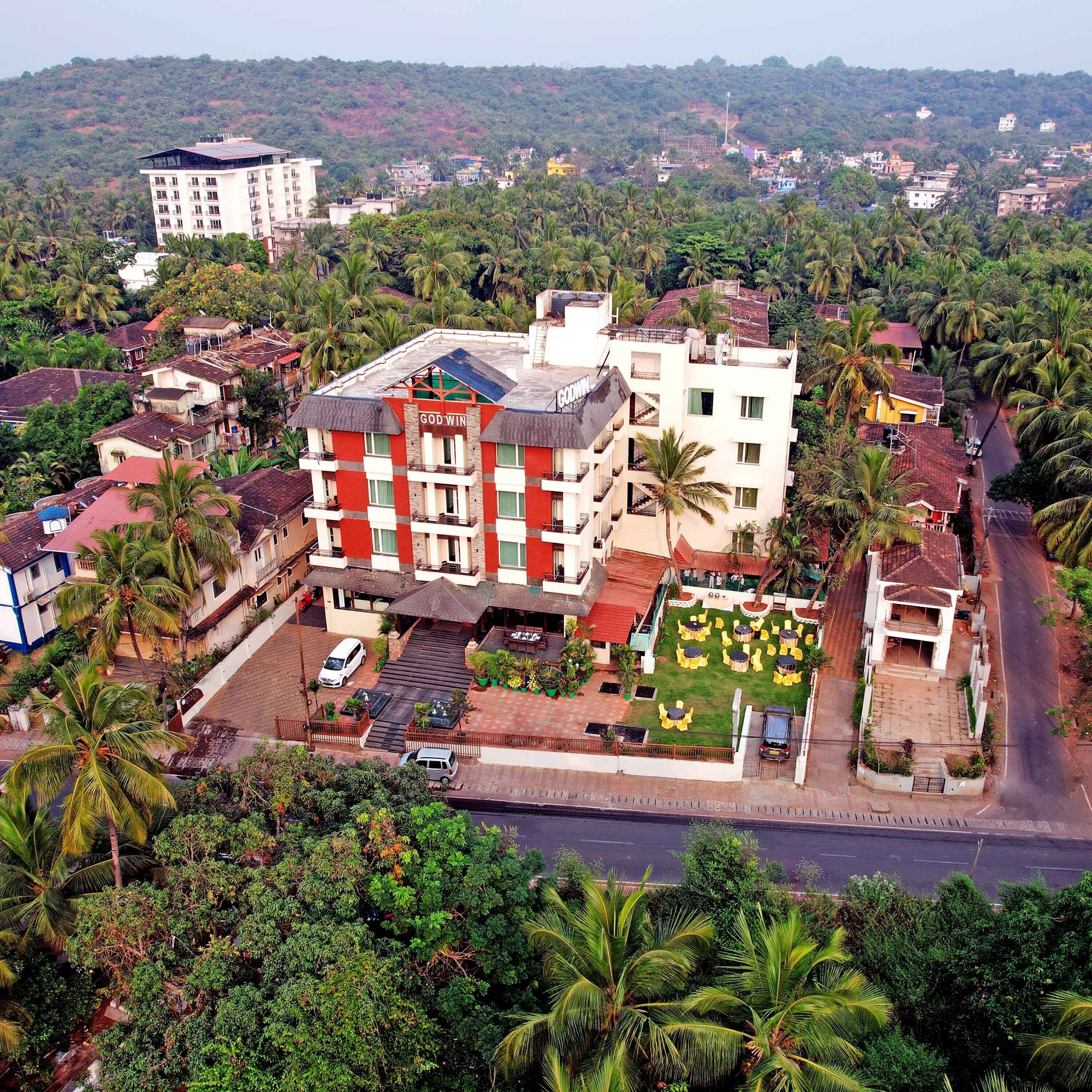 A multi-story hotel with a rooftop terrace and a well-maintained garden.