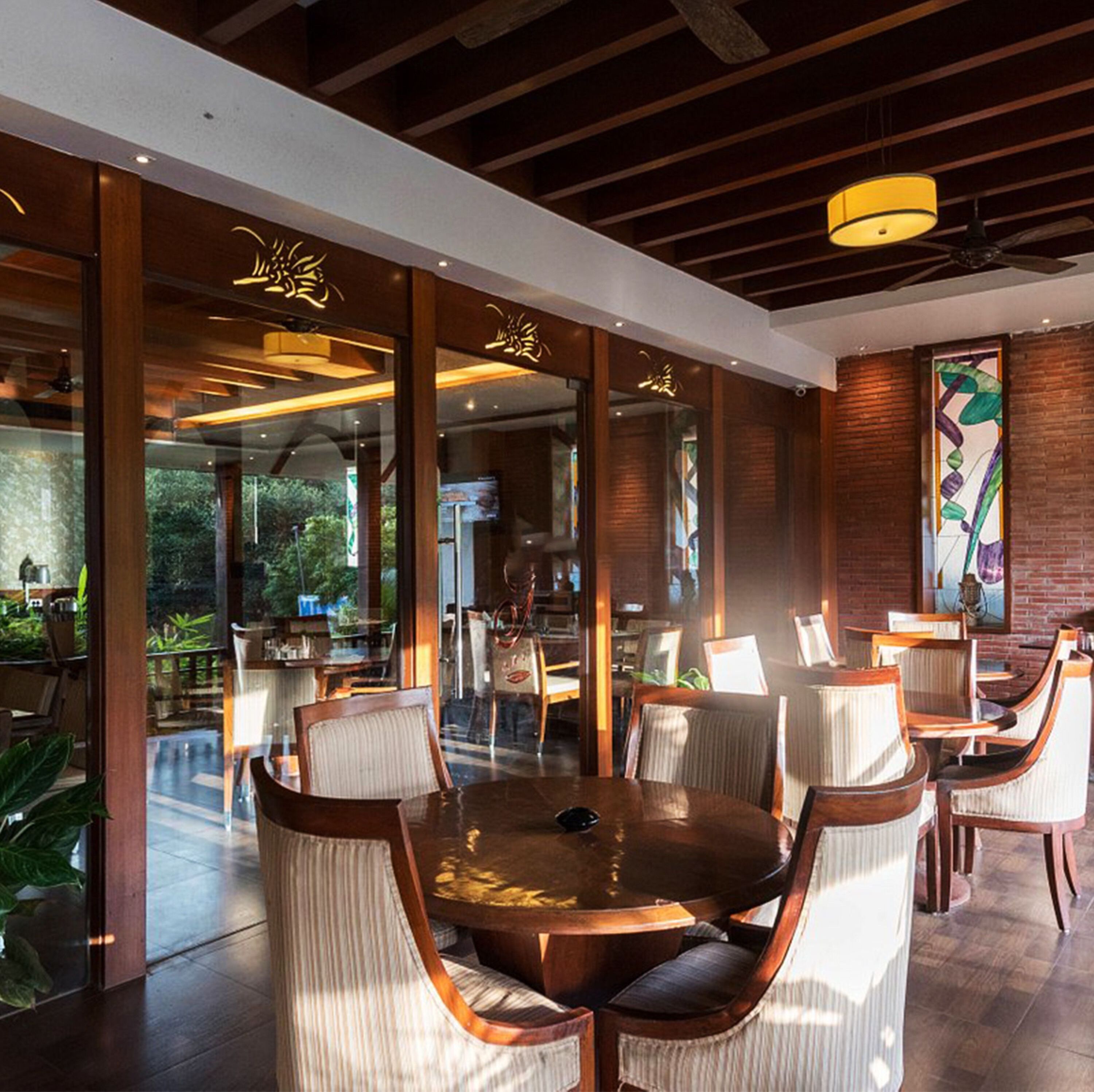 Un comedor moderno con mesas redondas y sillas acolchadas, ventanas amplias y vistas al exterior.