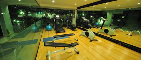 Une salle de sport équipée de matériel d’exercice, dotée d’un grand miroir et d’un plancher en bois.