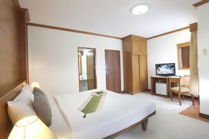 Una habitación de hotel con cama, escritorio con televisor, una silla y armario.