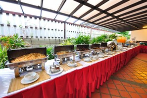Montaje de bufé con varias estaciones de comida y una larga mesa cubierta con un mantel rojo.