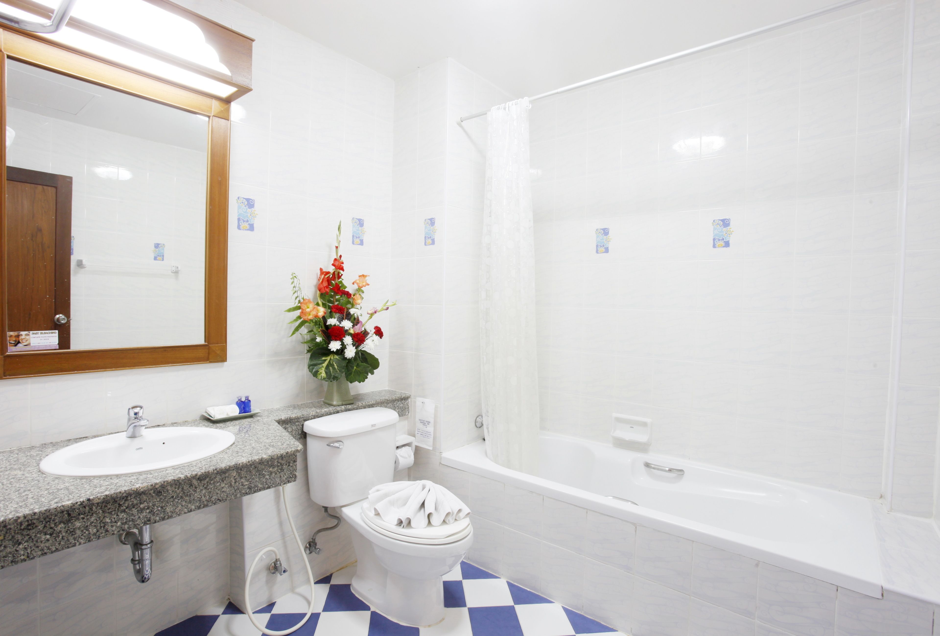 A bathroom with a white sink, toilet, and bathtub. There is a mirror above the sink and a shower curtain over the bathtub.