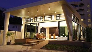A modern hotel with a covered entrance, large windows, and a staircase leading to the lobby.
