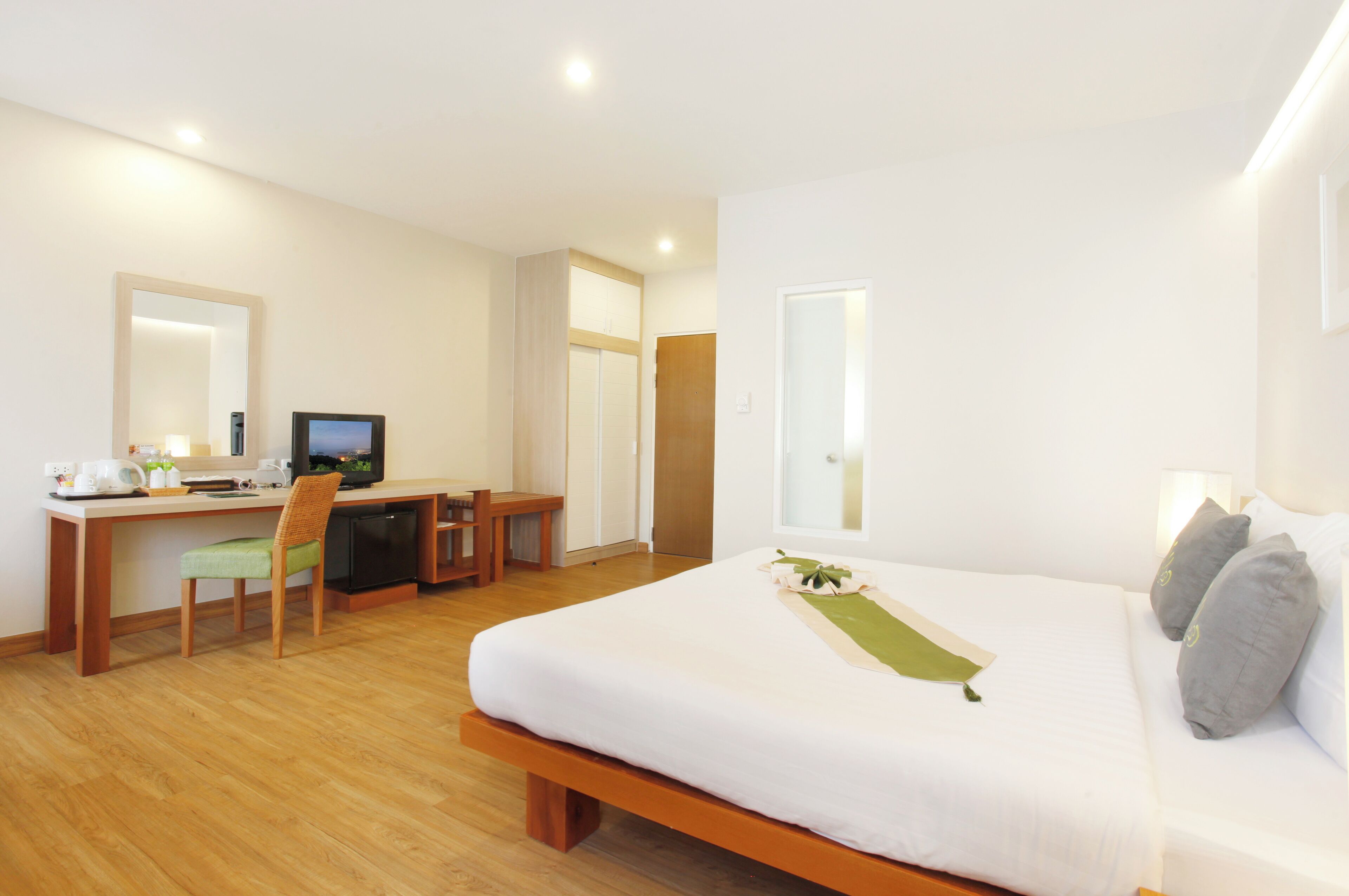 Una habitación de hotel con una cama, un escritorio con una computadora, una silla y una mesita.