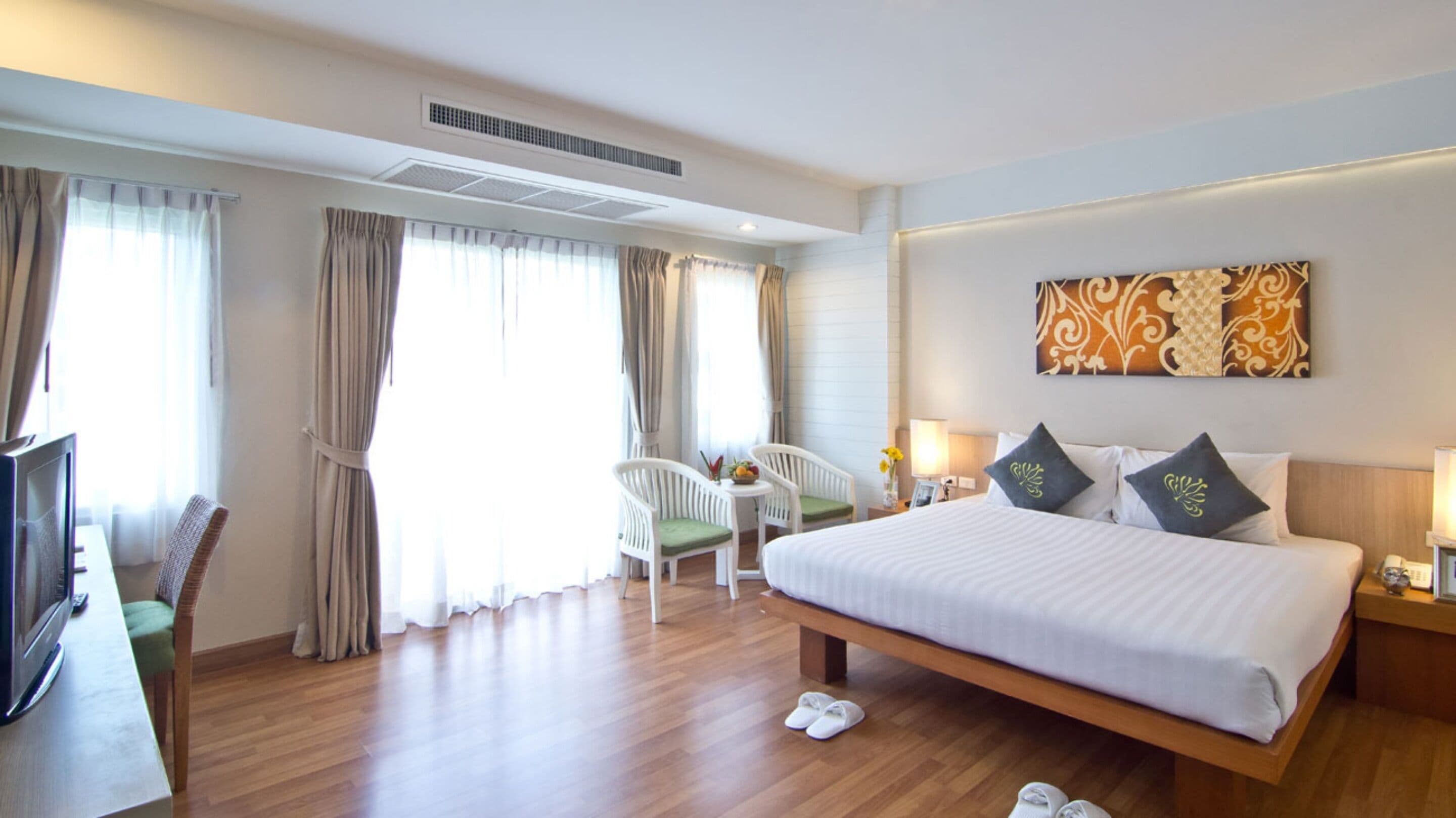 A hotel room with a large bed, a desk with a chair, and a television.