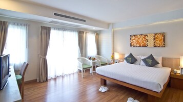 Una habitación de hotel con una cama grande, un escritorio con una silla y un televisor.