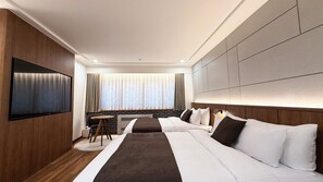 A modern hotel room with a large bed, a flat-screen TV mounted on the wall, and a small table with a chair.