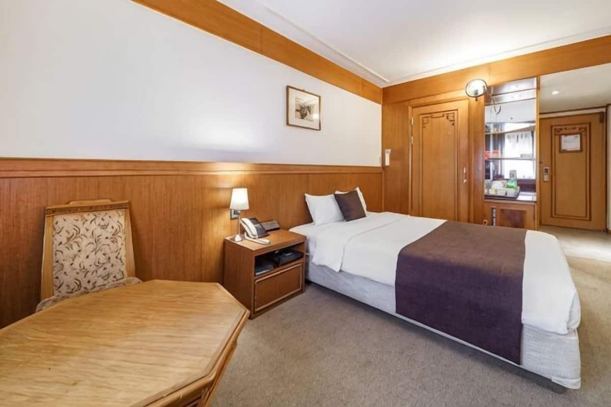 A hotel room with a bed, bedside table, lamp, and a mirror.