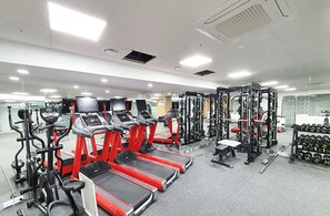Un gimnasio con cintas de correr, máquinas de pesas y mancuernas.