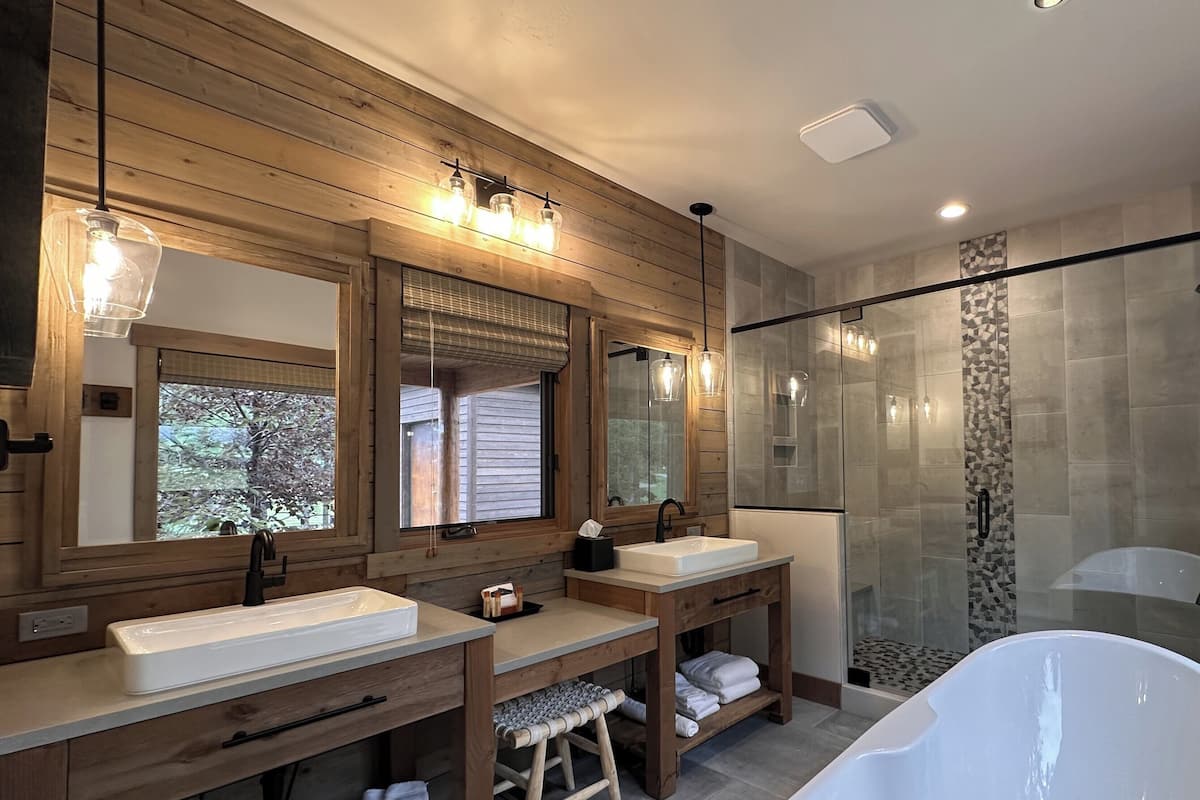 A modern bathroom with two sinks, a large bathtub, and a glass-enclosed shower.