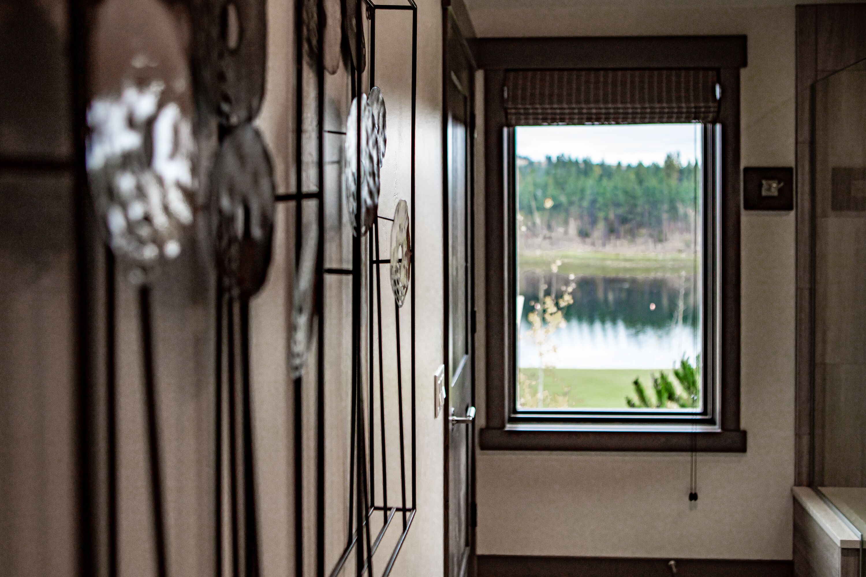 A hallway with a window overlooking a lake and forest.