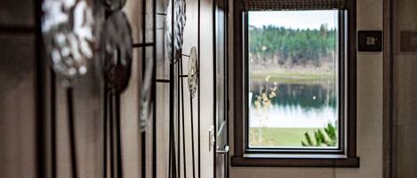 A hallway with a window overlooking a lake and forest.