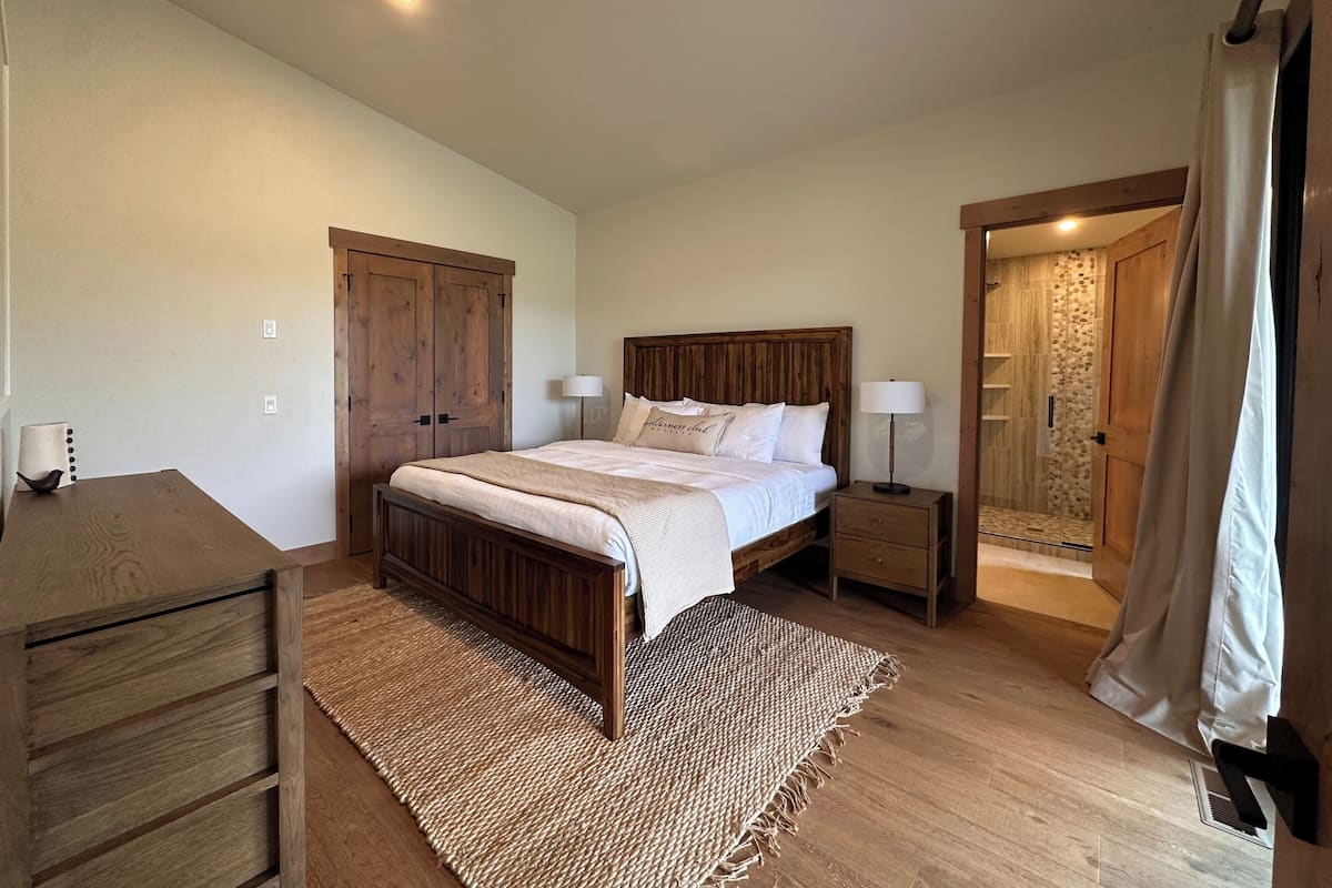 A bedroom with a wooden bed, nightstands, a desk, and a wardrobe.