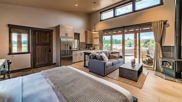A spacious bedroom with a large bed, a sofa, and a dining area with a kitchen.