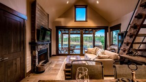 A cozy living room with a fireplace, a large window, and a dining area. - Wilderness Club (Eureka)