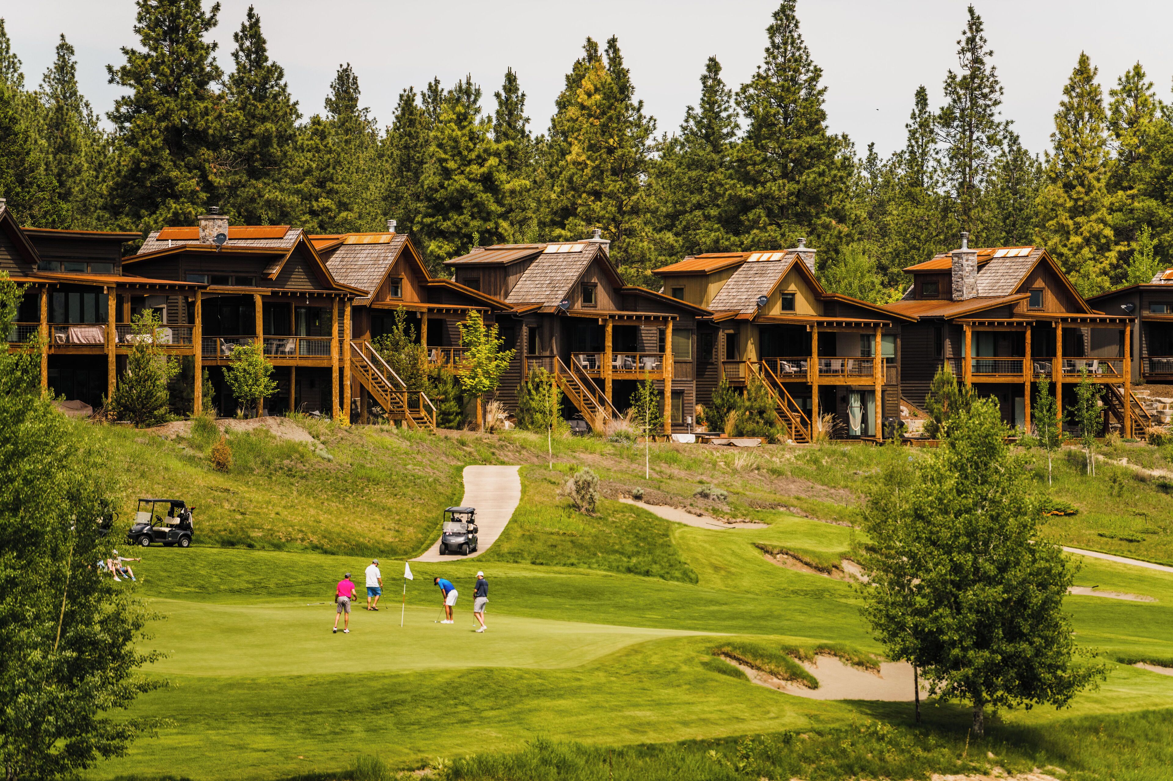Ein Resort mit mehreren Holzhäusern, einem Golfplatz und einem Parkplatz.