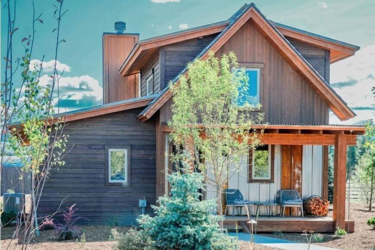 A wooden cabin with a porch, a chimney, and a small deck area.